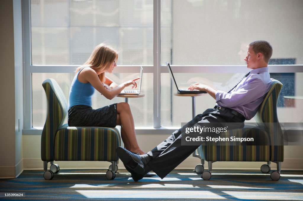 Businessman and woman at their laptops