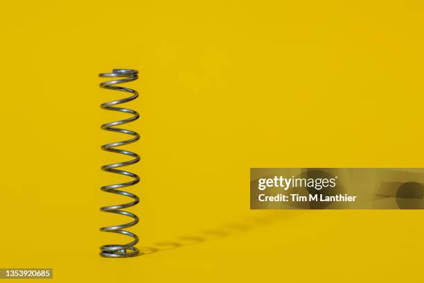 metal spring on yellow background - molla foto e immagini stock