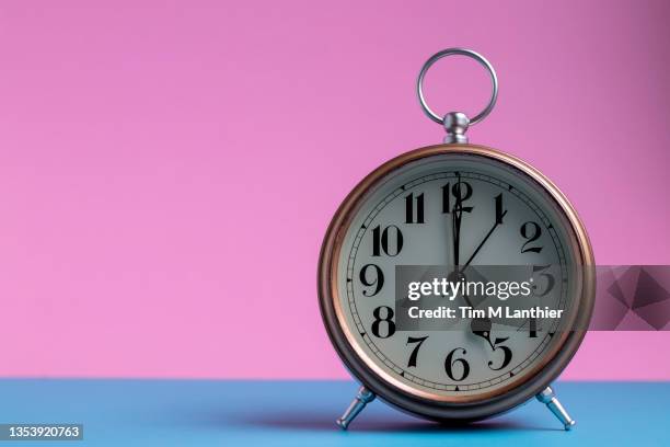clock against pink and blue background - 5 oclock alarm stock pictures, royalty-free photos & images