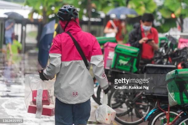 food delivery workers working on a rainy day in singapore - panda bike stock pictures, royalty-free photos & images