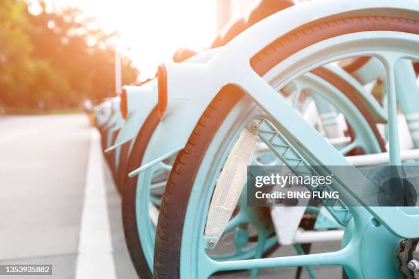 neatly arranged bicycles parked on the roadside - bicycle sharing system stock pictures, royalty-free photos & images