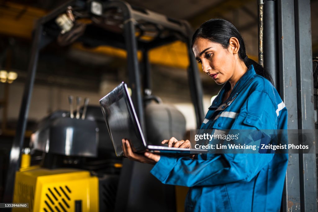 Trabalhador indiano da fábrica de aço feminino usando um laptop