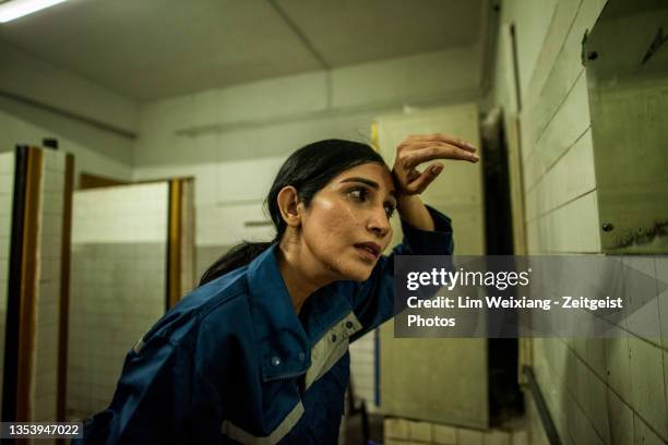 indische fabrikarbeiterin in toilette mit blick auf den spiegel - sweat stock-fotos und bilder