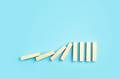 Falling pieces of dominoes on a clean blue minimal background. Business, risk, management and finance concept.