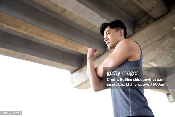 a young man doing warm-up exercises - viaduct ストックフォトと画像