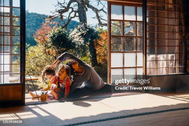 pregnant mother trying to do yoga while her daughters continue to disturb her - children funny moments stock pictures, royalty-free photos & images