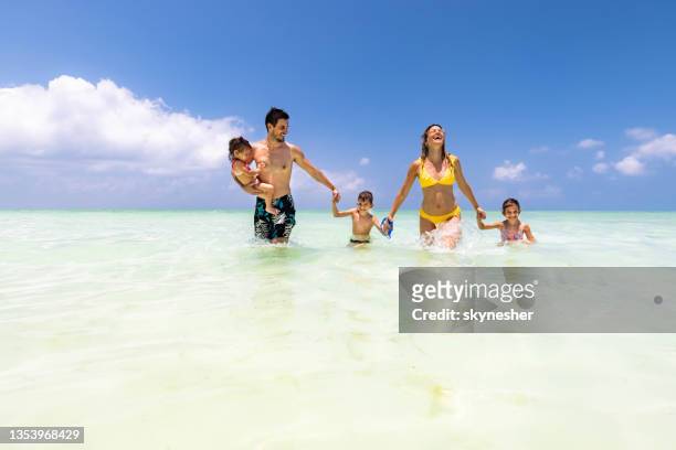 unbeschwerte familie händchen halten und durchs meer laufen. - boy and girl running along beach holding hands stock-fotos und bilder