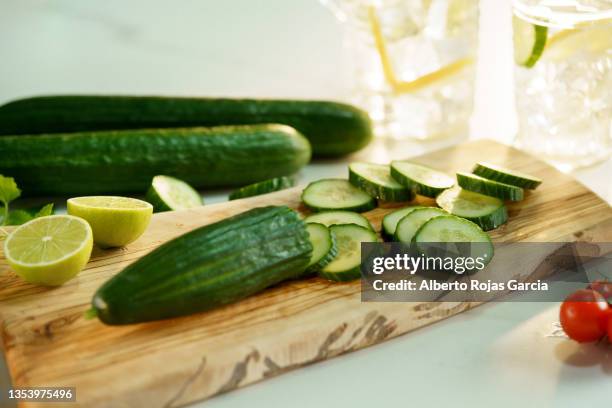 cucumber and lime on wooden cutting board for refreshing drink - cucumber stock-fotos und bilder