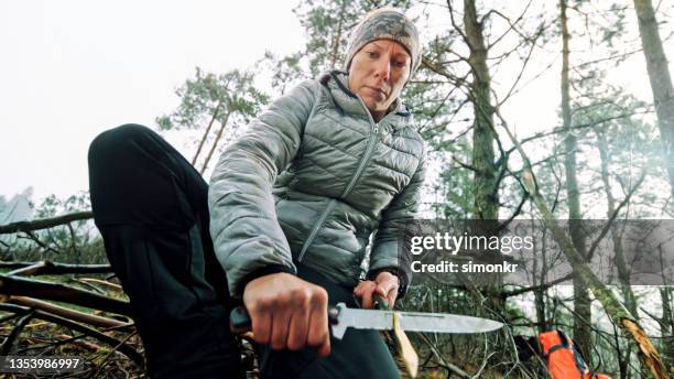 frau schärft das ende des astes im wald - survival stock-fotos und bilder