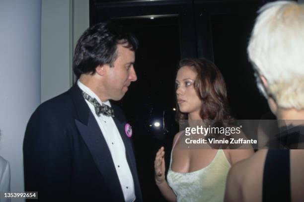 American actor and comedian Kevin Nealon, wearing a tuxedo and bow tie, and American actress Elizabeth Berkley, wearing a yellow vest top with pink...