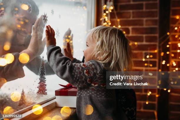 little boy playing with his father and christmas lights at home close to window - christmas lifestyle stockfoto's en -beelden