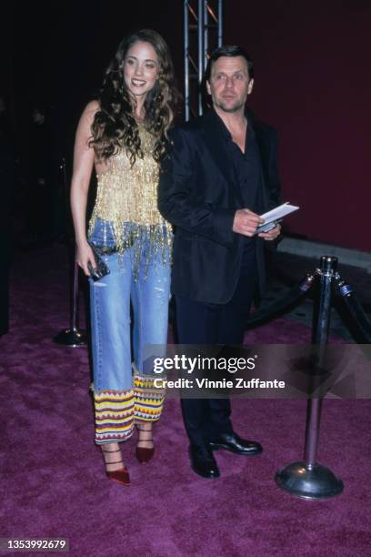American actress Elizabeth Berkley, wearing a gold fringed top with jeans, with multi-coloured hems, and a man attend the party celebrating the...
