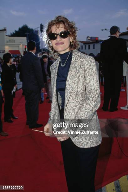 American actress and comedian Sandra Bernhard, wearing a grey leopard print-effect jacket over a dark blue turtleneck sweater and sunglasses, attends...