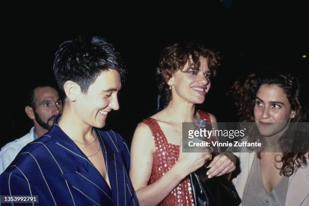 Canadian singer-songwriter kd lang, wearing a pinstripe blue jacket, and American actress and comedian Sandra Bernhard, wearing a red minidress, and...
