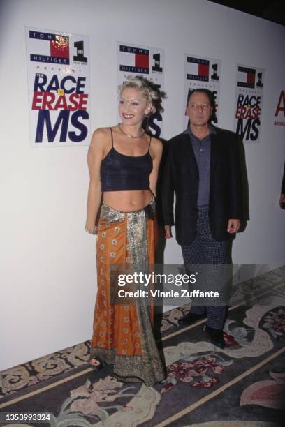 American singer Gwen Stefani, wearing a black crop top with an orange-and-silver wrap skirt, attends the 5th Annual Race to Erase MS Gala, held at...