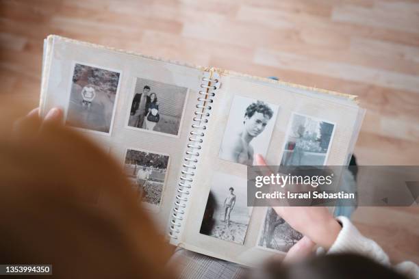 view from above of granddaughter looking at family album with her grandmother with alzheimer's to remember her husband. - album de photographies photos et images de collection