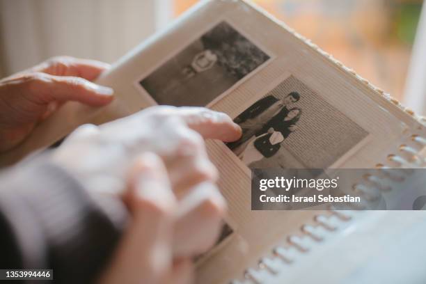 grandmother sharing memories and stories with her granddaughter while showing her an old family photo album. - reminder stockfoto's en -beelden