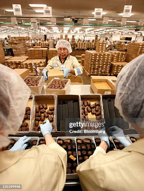 Belt stockers pack boxes of chocolates at the See's Candies Inc. Packing facility in South San Francisco, California, U.S., on Thursday, Dec. 8,...