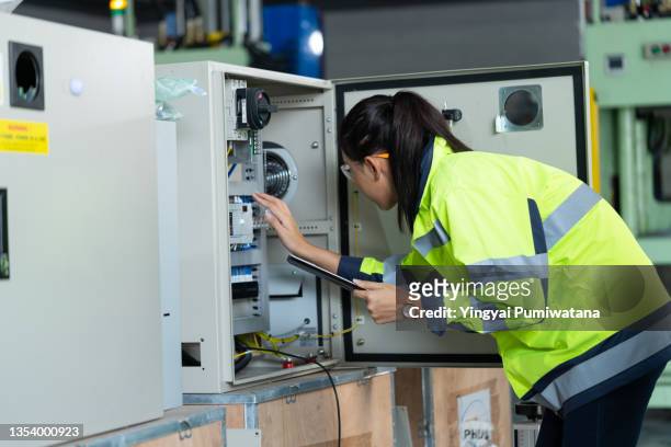 female technician or electrician engineer testing wires for voltage in a fuse cabinet.worker inspecting engineered automation machine in factory. - distribution board stock pictures, royalty-free photos & images