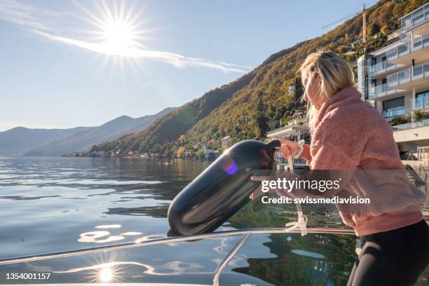 young woman on boat puts down fenders on lake - bumper stock pictures, royalty-free photos & images