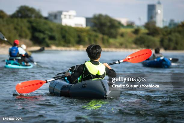 a group of adults enjoying canoeing and suping on a river in the city. - paddleboarding ストックフォトと画像