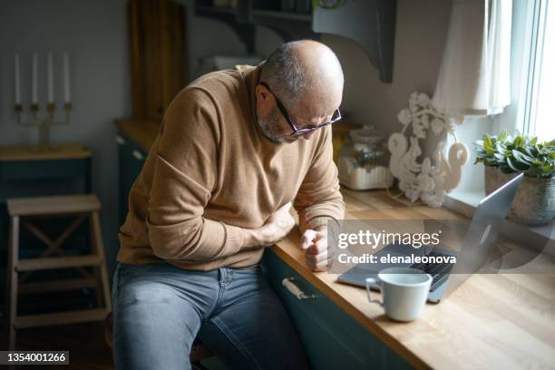 mature adult man in cozy interior of home kitchen ( laptop ,negative emotion ) - prostate stockfoto's en -beelden