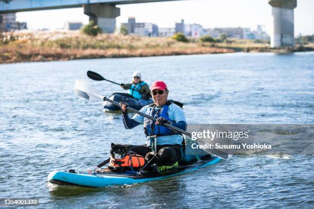 a group of adults enjoying canoeing and suping on a river in the city. - seniors canoeing stock pictures, royalty-free photos & images