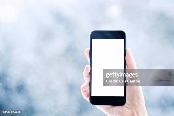 hand holding smartphone with blank screen on winter background - madrid snow stock pictures, royalty-free photos & images