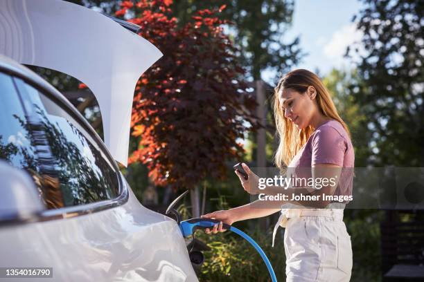 woman charging electric car - auto transmission stockfoto's en -beelden