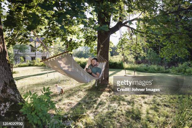 man lying in hammock in garden - rede imagens e fotografias de stock