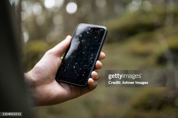 hand holding wet smart phone in forest - wetter stock pictures, royalty-free photos & images