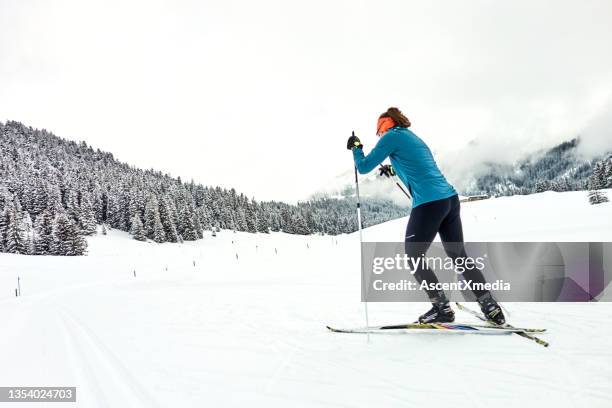 female skate skier follows track towards forest - nordic skiing event stock pictures, royalty-free photos & images