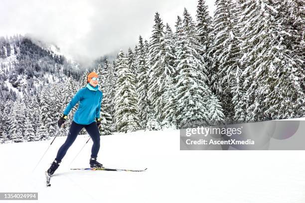 female skate skier follows track towards forest - cross country skiing tracks stock pictures, royalty-free photos & images