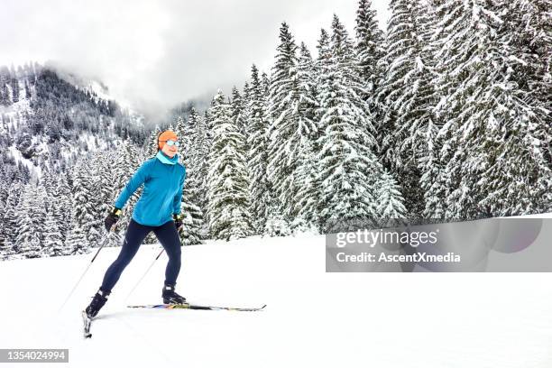 female skate skier follows track towards forest - 越野滑雪 個照片及圖片檔