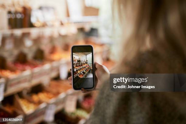 woman taking photo in shop with organic food - fotoberichten stockfoto's en -beelden