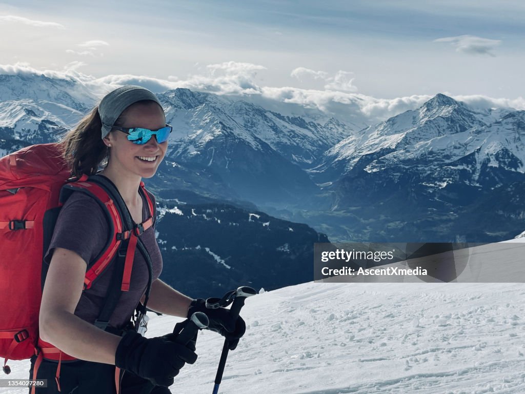 Female backcountry skier climbs snow slope