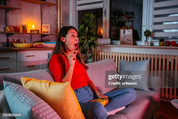 woman got surprised while watching movie and eating potato chips - movie night stock pictures, royalty-free photos & images