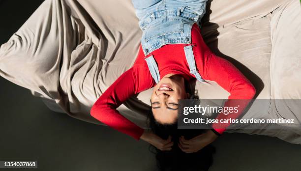 attractive young woman lies on the sofa at home while spending time with her alone quiet scene - fazer uma pausa imagens e fotografias de stock