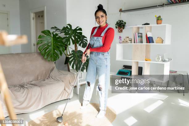 attractive woman stands in her living room while playing mini golf - mini golf stock-fotos und bilder