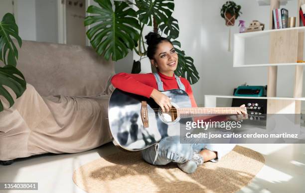 attractive woman plays a classical guitar sitting on a carpet happy and calm - guitariste photos et images de collection