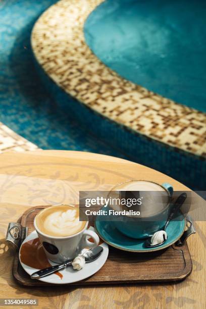 two cups with latte art on wooden table by the pool - pool table stock-fotos und bilder