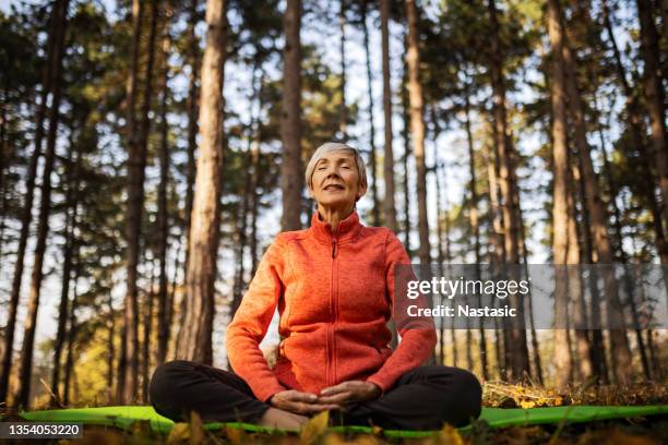 mujer mayor practicando la rutina de ejercicios de yoga - meditation outdoors fotografías e imágenes de stock