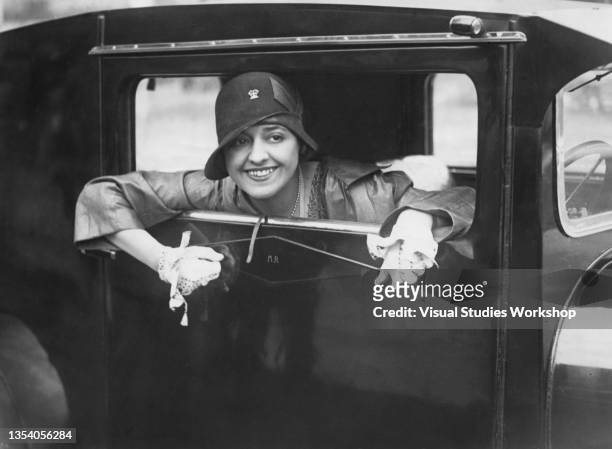 Portrait of French dancer and actress Marcelle Rahna as she smiles out of the driver's side window of her car at Velodrome de Parc des Princes,...