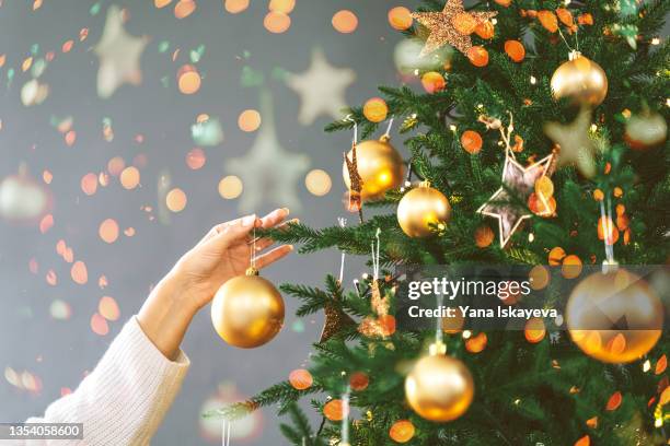elegant woman hand decorating a christmas tree, illuminated bokeh lights overlay - decorare l'albero di natale foto e immagini stock