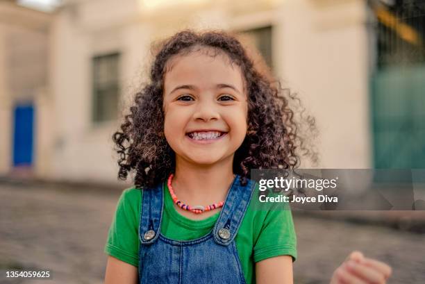 通りで微笑む小さな女の子。 - brazilian children ストックフォトと画像