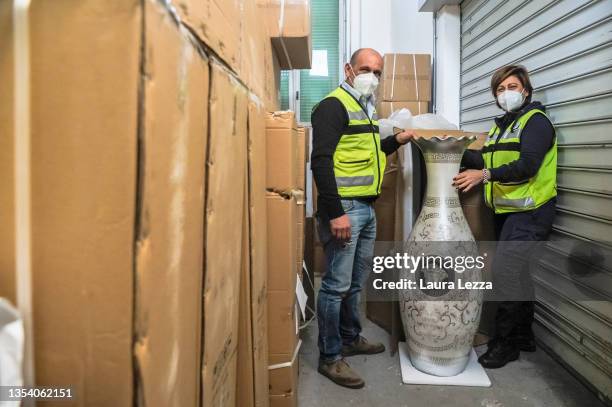 Two officials of the Ufficio delle Dogane di Livorno check the shipment of counterfeit confiscated goods and furniture items with the Versace logo...