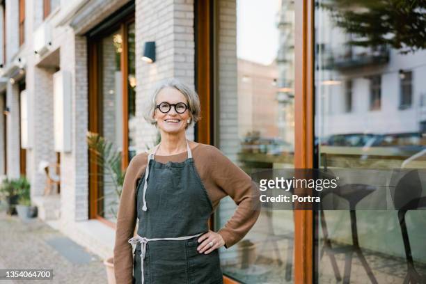 senior woman in front of a coffee shop. - store manager stock pictures, royalty-free photos & images