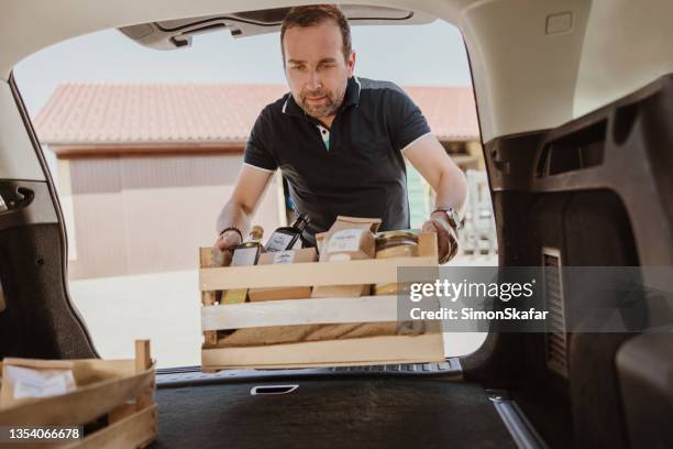 man carrying food products crate in car trunk - picking up food stock pictures, royalty-free photos & images