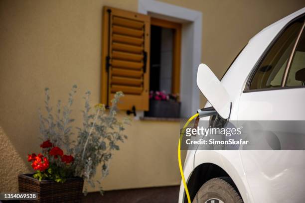charging an electric car at home - electric car home stock pictures, royalty-free photos & images