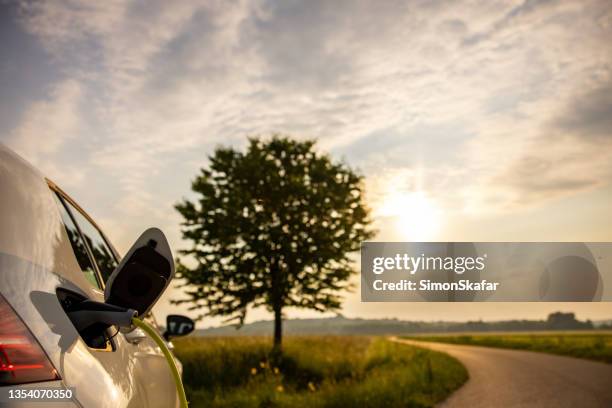 charging an electric car on agriculture field at roadside - hybrid cloud stock pictures, royalty-free photos & images